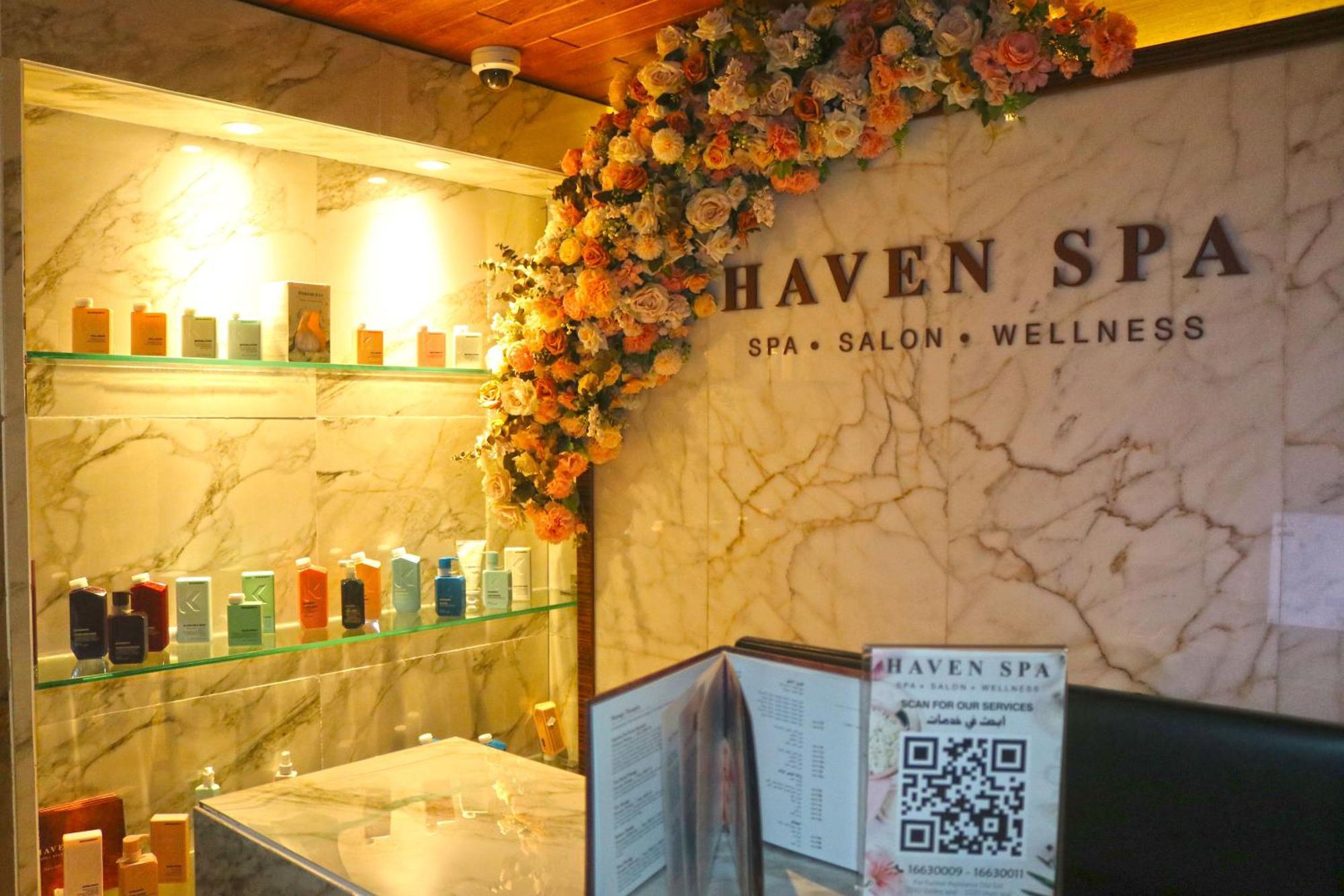 Lagoona Beach Luxury Resort And Spa Manama Ngoại thất bức ảnh The photo shows the interior of a spa called "Haven Spa." The wall is decorated with beautiful artificial flowers, creating an inviting atmosphere. There are several shelves displaying various colorful bottles and products, likely for skincare or wel