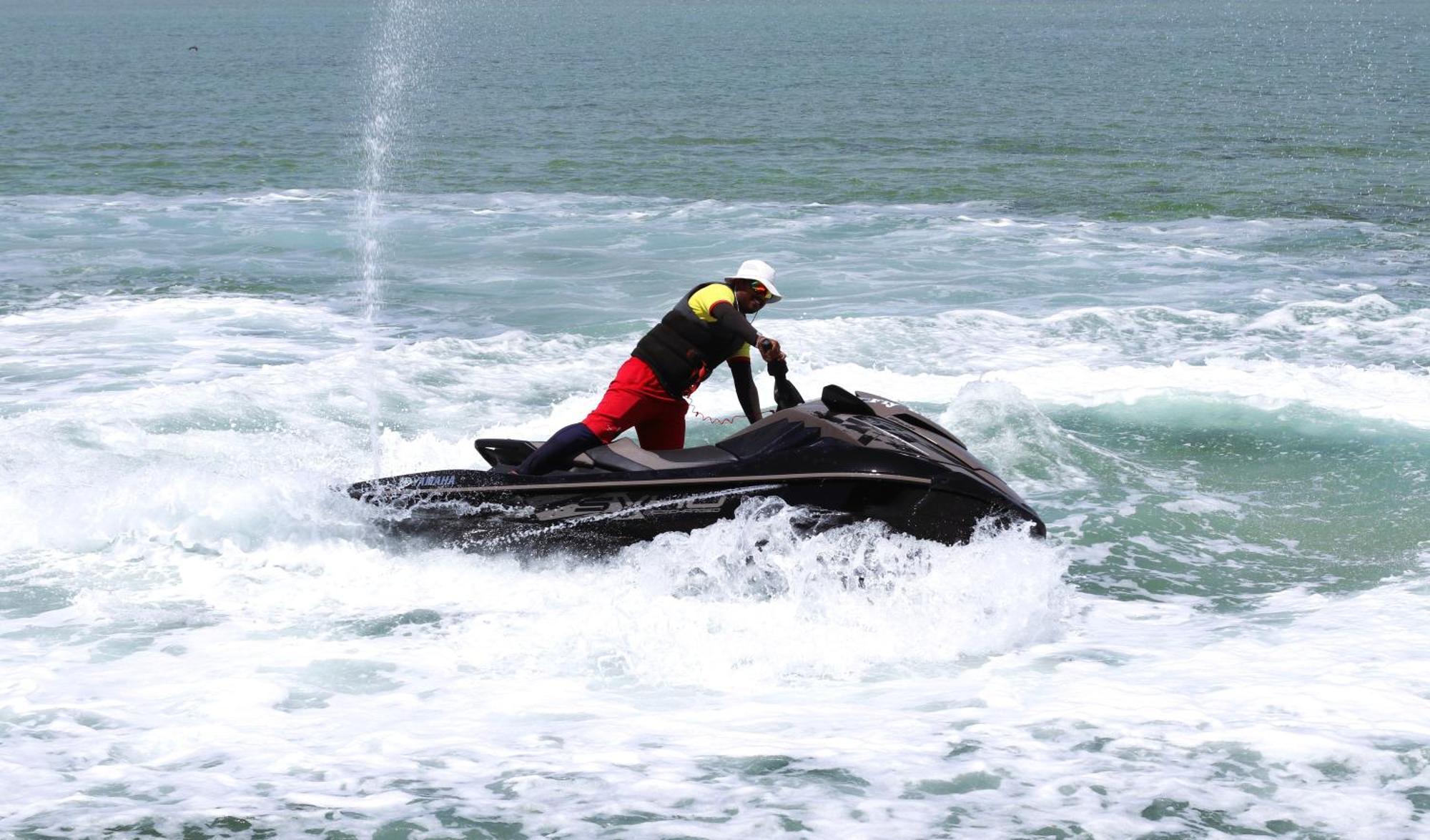 Lagoona Beach Luxury Resort And Spa Manama Ngoại thất bức ảnh The photo shows a person riding a jet ski on the water. The rider is positioned upright, leaning forward with one hand on the handlebars, while the jet ski creates splashes of white foam around it. The water appears choppy, likely due to the motion o