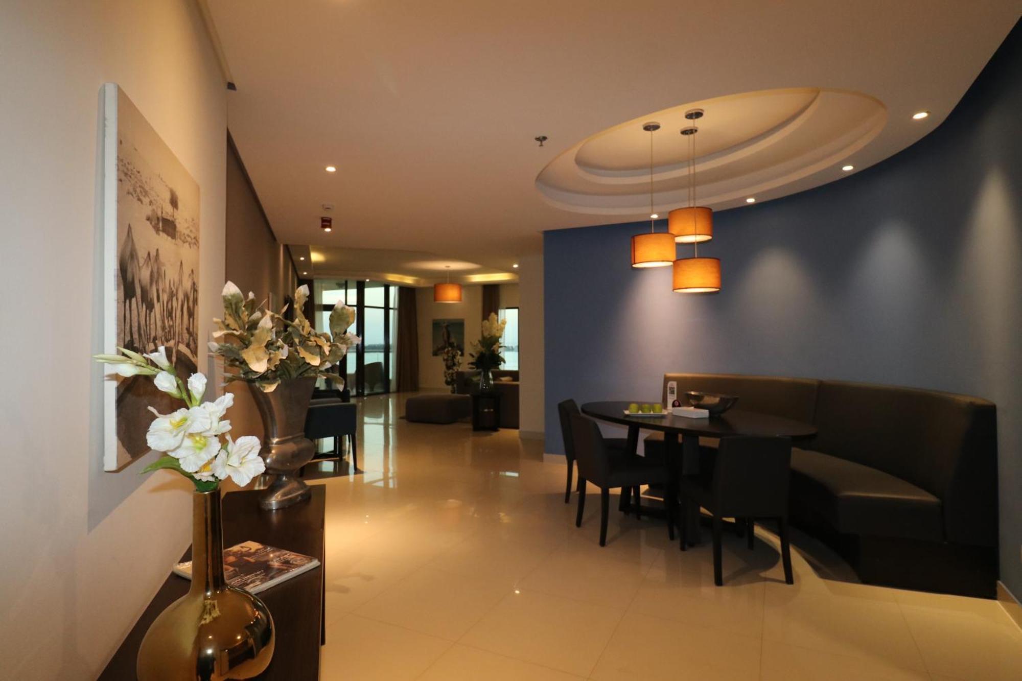 Lagoona Beach Luxury Resort And Spa Manama Ngoại thất bức ảnh The photo showcases an interior space, likely a modern lounge or reception area. It features a combination of soft lighting, neutral-colored walls, and decorative elements. There are elegant light fixtures hanging from the ceiling, and a curved blue 