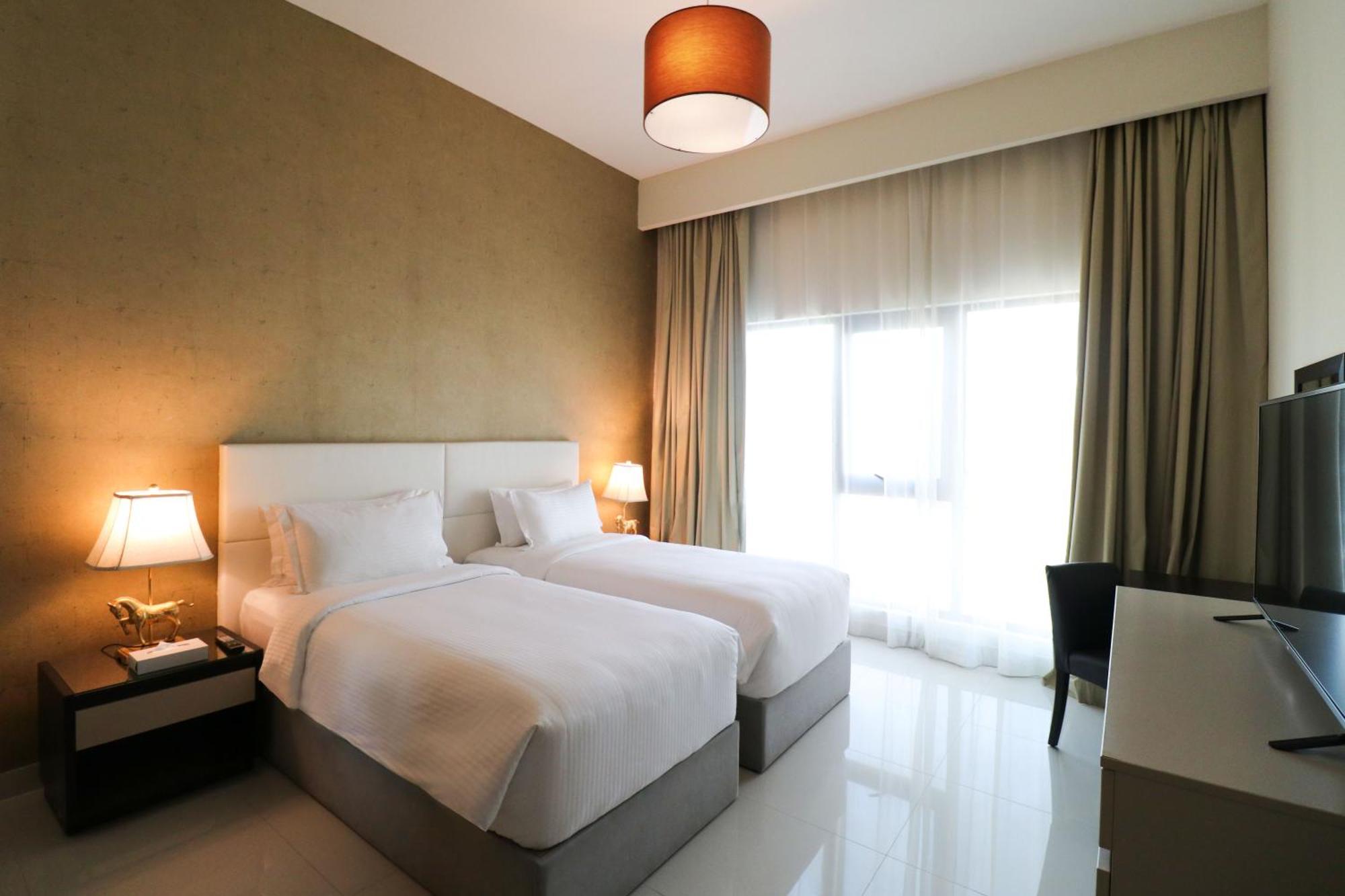 Lagoona Beach Luxury Resort And Spa Manama Ngoại thất bức ảnh The photo shows a hotel room featuring two single beds with white bedding. The walls have a neutral tone, and there's a large window covered by light, sheer curtains allowing natural light to enter. On either side of the beds, there are bedside table